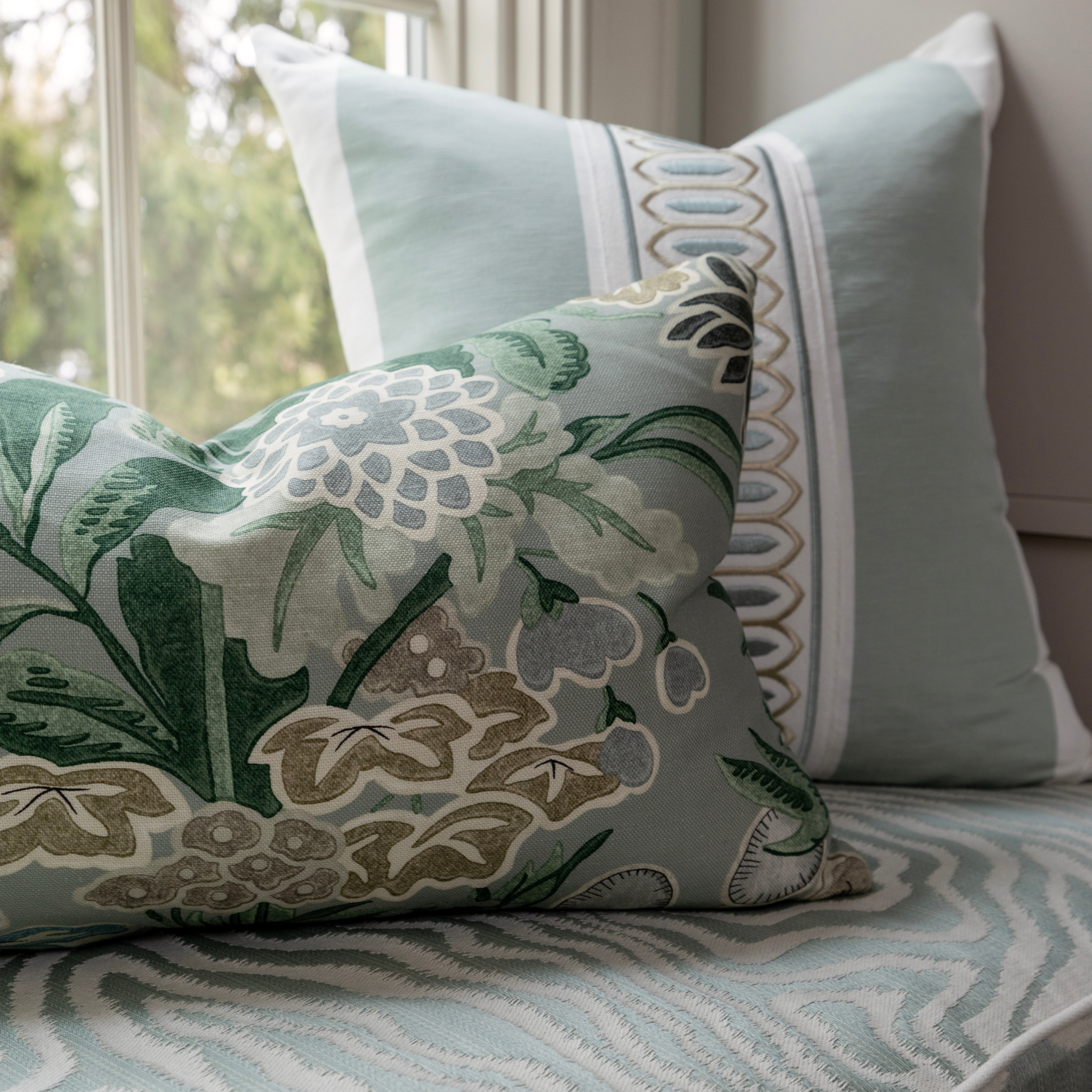 Decorative custom upholstered pillows with floral and geometric patterns on a bench by Peppard Home + Interiors in Huntington, NY