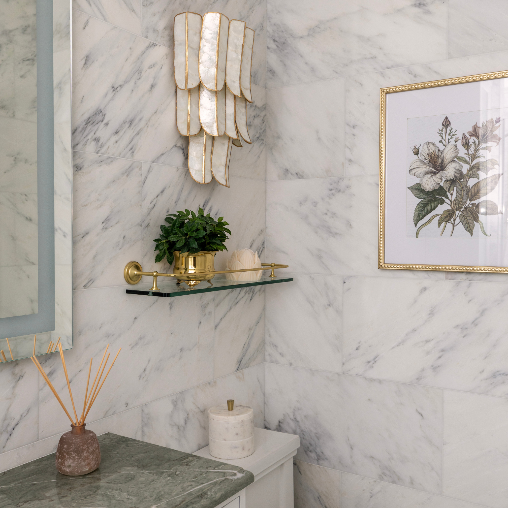 Bathroom interior design with marble walls, decorative light fixture, plant, and artwork Huntington, NY